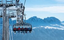 Wintersportler sitzen auf einem Sessellift vor einer Bergkulisse | © Bergbahnen Flumserberg AG