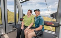 Älteres Paar sitzt lächelnd in einer Gondel bei einer Bergfahrt | © Bergbahnen Flumserberg AG