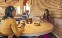 Drei Personen geniessen ein Fondue im Innern einer Berghütte  | © Bergbahnen Flumserberg AG