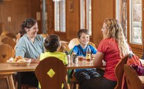 Zwei Frauen und zwei Kinder sitzen gemeinsam an einem Tisch mit Gipfeli in einem Korb | © Bergbahnen Flumserberg AG