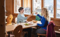 Zwei Frauen stossen in einem Restaurant gemeinsam mit einem Glas Wein an | © Bergbahnen Flumserberg AG