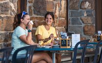 Zwei Frauen trinken auf einer Terrasse einer Berghütte einen Kaffee | © Bergbahnen Flumserberg AG