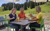 Drei Erwachsene essen gemeinsam Mittag an einem Tisch draussen | © Bergbahnen Flumserberg AG