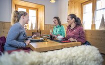 Drei junge Frauen gemeinsam beim Essen in einer Berghütte | © Bergbahnen Flumserberg AG