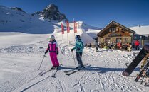 Zwei Skifahrerinnen stehen auf den Ski vor einer Berghütte | © Bergbahnen Flumserberg AG