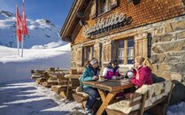 Drei Frauen in Skikleidung trinken im Winter einen Kaffee auf einer Terrasse einer Berghütte | © Bergbahnen Flumserberg AG