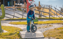 Kleiner Junge auf einem Laufrad fährt über ein Parcourshindernis | © Bergbahnen Flumserberg AG