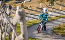 Kleiner Junge fährt auf einem Minitrail eine Kurve auf einem Laufrad | © Bergbahnen Flumserberg AG