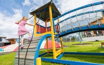 Mädchen klettert auf einem Spielplatz über Holzrampe | © Bergbahnen Flumserberg AG
