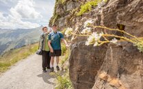 Älteres Paar wandert auf einem Bergweg entlang einer Felswand | © Bergbahnen Flumserberg AG