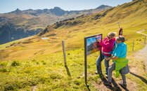 Zwei Wanderer betrachten eine Informationstafel in einer Berglandschaft | © Bergbahnen Flumserberg AG