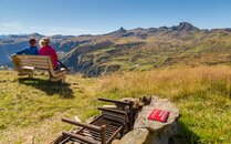 Ein Paar sitzt auf einer Bank und bewundert das Bergpanorama, im Vordergrund eine Feuerstelle | © Bergbahnen Flumserberg AG