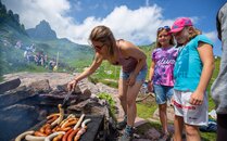 Schulklasse grillt Würste auf einer Feuerstelle im Berg | © Bergbahnen Flumserberg AG