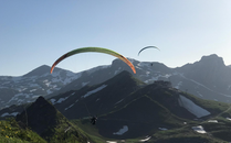 Zwei Gleitschirmflieger über einer Berglandschaft, teilweise noch Schneefelder | © Bergbahnen Flumserberg AG