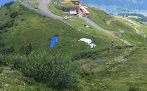Berglandschaft mit Bergstation und Gleitschirmflieger bei Startvorbereitungen | © Bergbahnen Flumserberg AG