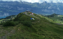 Grüne Wiesen einer Berglandschaft mit Bergstation im Hintergrund | © Bergbahnen Flumserberg AG