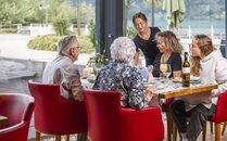 Vier Personen sitzen an einem Tisch im Restaurant mit Seeblick | © Bergbahnen Flumserberg AG