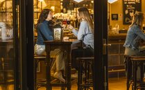 Zwei junge Frauen stossen mit Getränken in einer Bar an | © Bergbahnen Flumserberg AG