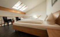Hotelzimmer auf einer Galerie mit Bett und zwei Stühlen | © Bergbahnen Flumserberg AG