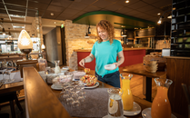 Frau steht am Frühstücksbuffet und schöpft sich Fruchtsalat | © Bergbahnen Flumserberg AG