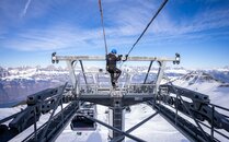 Techniker führt Wartungsarbeiten an einer Seilbahnstation mit verschneiter Bergkulisse aus | © Bergbahnen Flumserberg AG