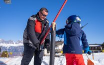 Mann hilft Kind beim Start des Bügellifts | © Bergbahnen Flumserberg AG