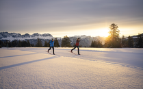 Zwei Personen beim klassischen Langlaufen mit Sonnenuntergang in einer verschneiten Winterlandschaft | © Bergbahnen Flumserberg AG