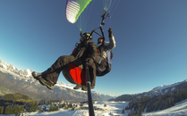 Zwei Gleitschirmflieger in der Luft in einem Tandemflug über einer verschneiten Winterlandschaft | © Bergbahnen Flumserberg AG